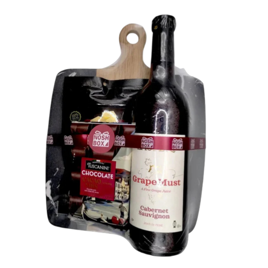 A gift package consisting of an acacia and marble cheese board with a handle, a bottle of Cabernet Sauvignon grape must, a package of cheese puffs and a chocolate bar, wrapped with shrink wrap and a burgundy ribbon.